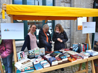 Drei Frauen stehen hinter einem Bücherstand.