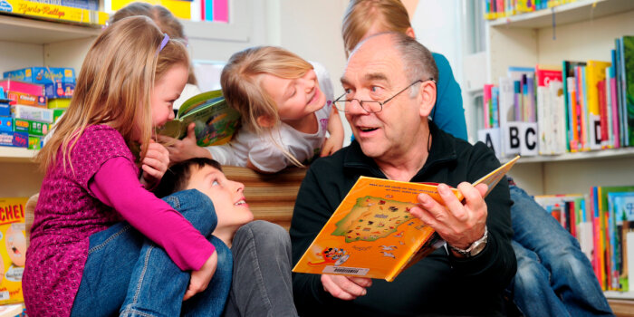 Mann liest Kindern ein Buch vor