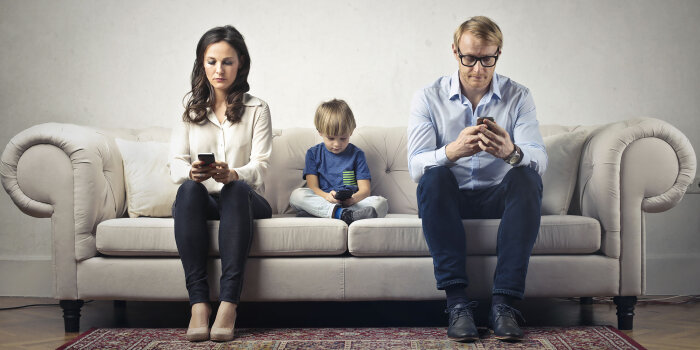 Familie sitzt mit Smartphone auf einem Sofa