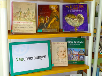 Ein mit Büchern gefülltest Regal mit der Beschriftung Neuerwerbungen.