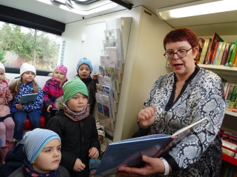 Frau liest Kindern aus einem Buch vor.