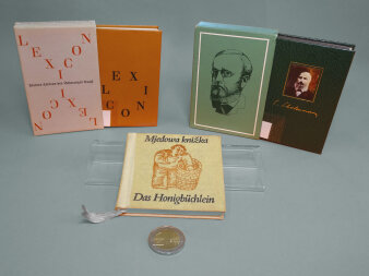 Abgebildet sind drei Minibücher und eine Zwei-Euro-Münze als Größenvergleich.