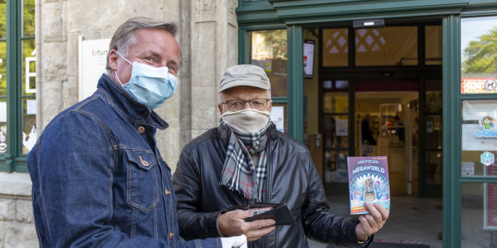 Zwei Männer mit Masken vor dem Eingang zur Bibliothek.