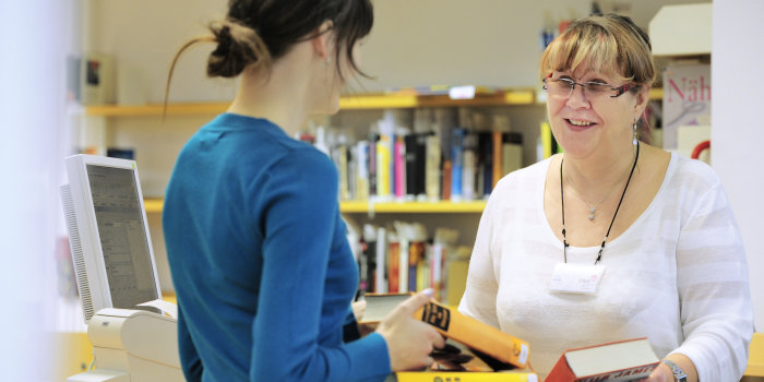 Eine Bibliothekarin verbucht ausgeliehene Medien.