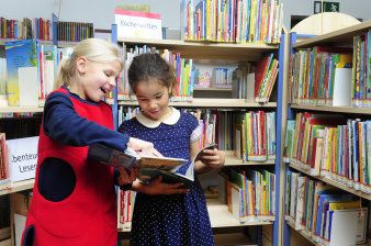 Zwei Mädchen lesen ein Buch in einer Bibliothek