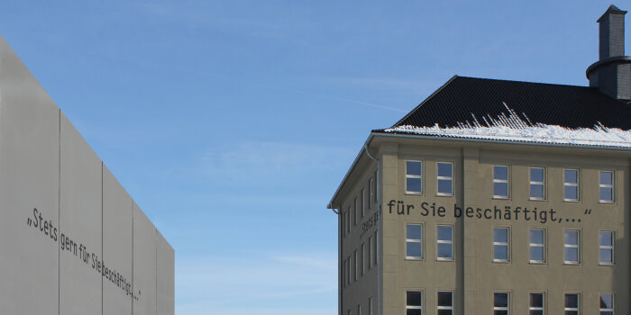 Foto: Außenansicht des Erinnerungsortes Topf & Söhne mit Schriftzug © Erinnerungsort Topf & Söhne Detailansicht des Gebäudes "Topf & Söhne" mit dem Schriftzug "Immer gern für Sie beschäftigt"