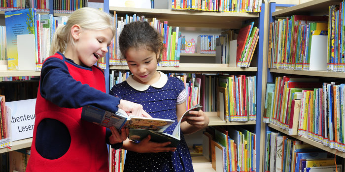 Foto: Kinder lesen vor © Barbara Neumann Zwei Mädchen lesen ein Buch in einer Bibliothek