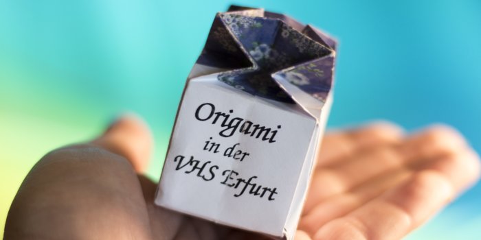 Foto: Kleine Geschenkverpackungen selbst gemacht © Stadtverwaltung Erfurt / Grit Kästner Auf einer Hand liegt eine im Origami gefertigte Geschenkverpackung mit der Aufschrift: "Origami in der VHS Erfurt".