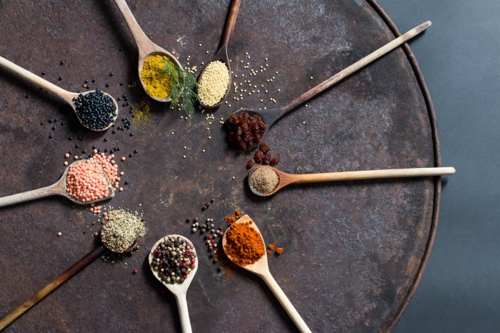 Kochen ayurvedisch Kochlöffel mit Gewürzen im Kreis angeordnet.