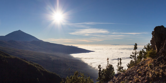 Gegenlichtfoto mit bewachsenen Bergen und Wolken im Tal