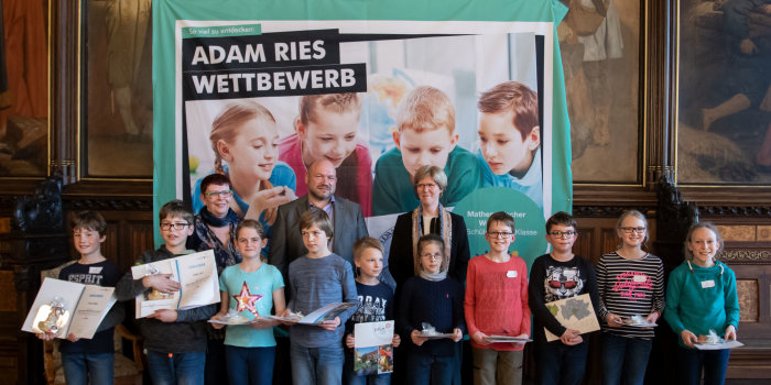 Foto: Die Teilnehmer des Adam-Ries-Wettbewerbes © Stadtverwaltung Erfurt Kinder und Erwachsene vor einer Präsentationswand.