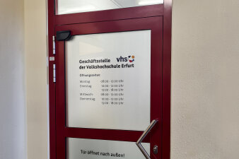 die neue Eingangstür zur VHS-Geschäftsstelle, auf welcher die Öffnungszeiten stehen