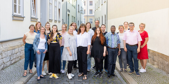 Zu sehen sind die Mitarbeiter und Mitarbeiterinnen des Teams der Volkshochschule Erfurt in eine Outdooraufnahme.