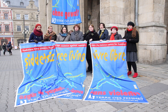 Aktivistinnen des Frauennetzwerk mit Fahne vor dem Rathaus.