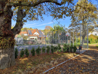 eingezäunter Bolzplatz mit Basketballkorb