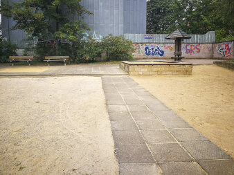 ein alt anmutender Spielplatz mit großen Sandflächen