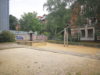 ein alt anmutender Spielplatz mit großen Sandflächen