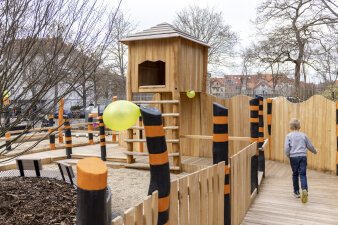 ein Spielplatz, ein Kind rennt über einen Holzsteg