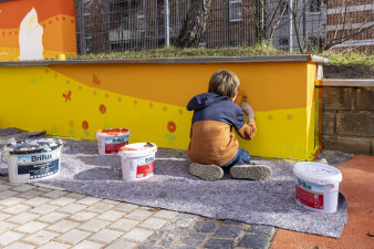 ein Kind bemalt eine Mauer mit Farbe