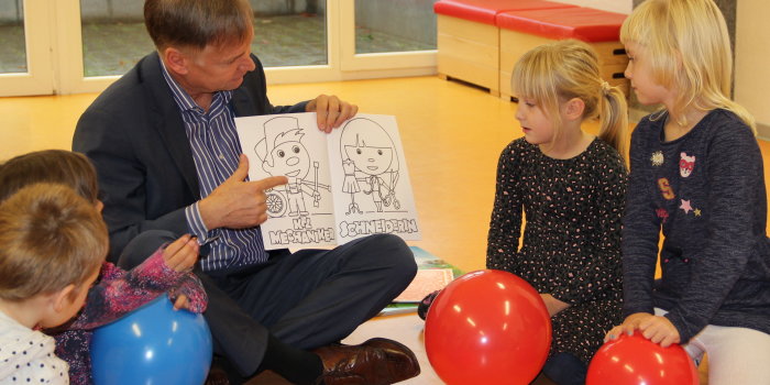 Mann sitzt im Schneidersitz in Kindergruppe.