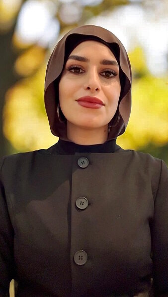 Eine Frau mit einem braunen Kopftuch (Hijab) lächelt in die Kamera