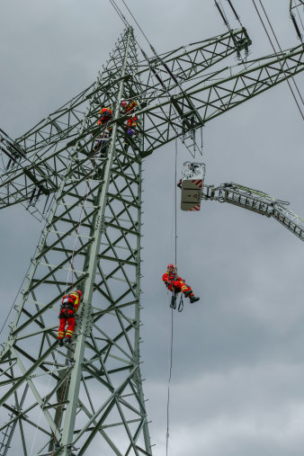 Ein Feuerwehrmann seilt sich von einem Strommast ab.