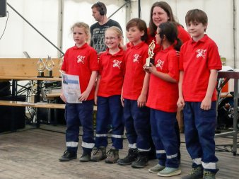 Kinder der Jugendfeuerwehr Erfurt-Hochheim halten einen Siegerpokal und eine Urkunde in den Händen. Glücklich stehen sie mit ihrer Betreuerin im Festzelt auf der Bühne.