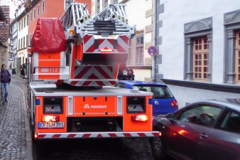 Drehleiterfahrzeug der Feuerwehr in einer engen Straße von Pkw behindert