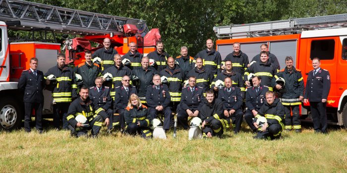 Feuerwehrleute in Einsatzbekleidung vor zwei Einsatzfahrzeugen