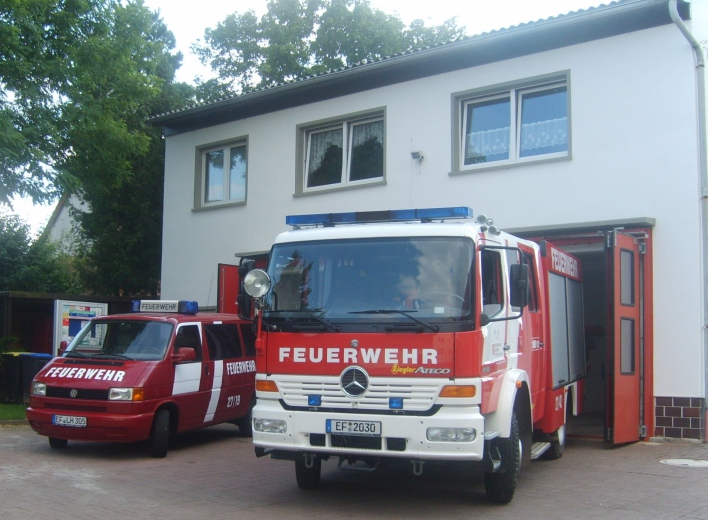 Zwei Feuerwehrfahrzeuge stehen vor den geöffneten Toren des Feuerwehrhauses