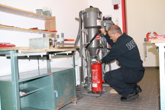 Feuerwehrmann beim Befüllen eines Pulver-Feuerlöschers in der Werkstatt
