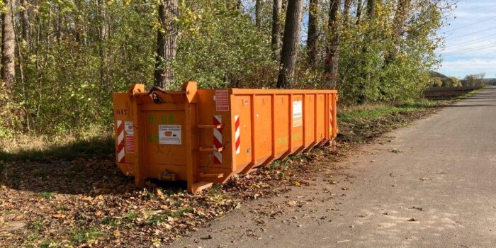 Grüncontainer zum Sammeln von Grünabfällen aufgestellt an einem Waldrand.