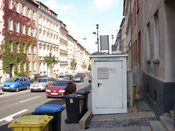 Das Foto zeigt die Luft-Messstation in der Bergstraße mit vorbeifahrendem Autoverkehr.