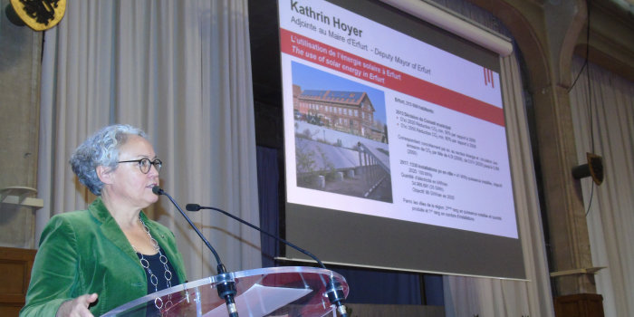 Foto: Am Runden Tisch zur „Nachhaltige(n) Entwicklung“ erläuterte Kathrin Hoyer kürzlich in Erfurts Partnerstadt Lille die Umweltvorhaben für die nächsten 30 Jahre. © Stadtverwaltung Erfurt Frau am Mikrofon, im Hintergrund eine Präsentation.
