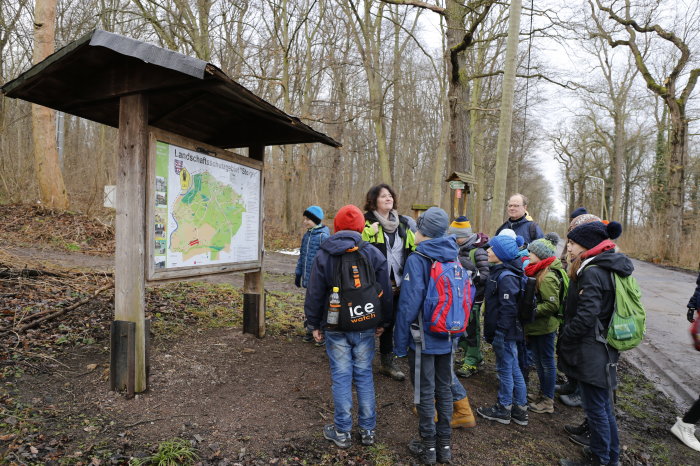 Uta Krispin erklärt den Wald: Försterwanderung zum Familientag auf der Fuchsfarm Försterin steht mit Kindern am Waldrand.
