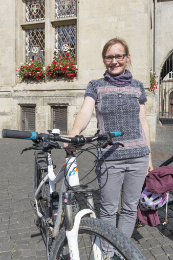 Freundlich schauende junge Frau mit Fahrrad.