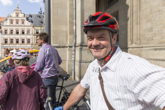 Ein Mann mit Fahrradhelm lacht freundlich in die Kamera.