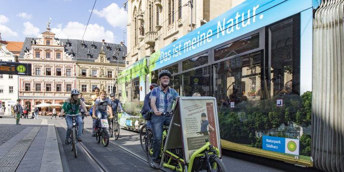 Fahrradfahrer neben einer grünen Straßenbahn