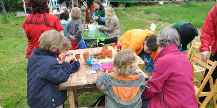 Foto: Familientag 2014 - viele interessante Bastelstände © Stadtverwaltung Erfurt Kinder befüllen am Bastelstand kleine Tontöpfe mit Samen und Erde und beschriften die Töpfe. Im Hintergrund sind weitere Stände zu sehen.