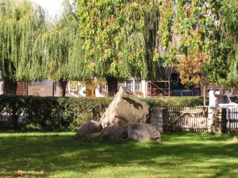 große Steine auf eingezäunter Grünfläche mit Bäumen im Hintergrund