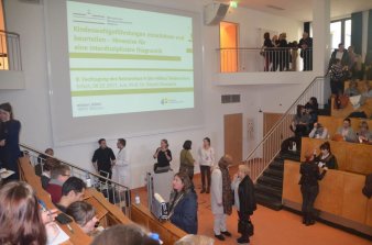 Foto: Vortrag Kindeswohlgefährdung einschätzen © Stadtverwaltung Erfurt Das Bild zeigt das Auditirium im Helios Klinikum Erfurt, in dem an die Wand ein Vrotrag projeziert wird. Mehrere Personen haben sich zur Diskussion versammelt.
