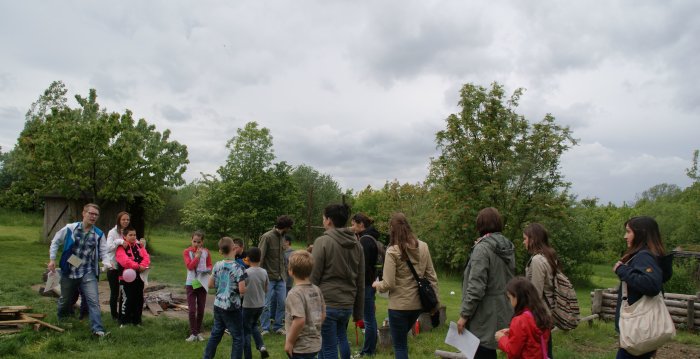 Foto: Kinder- und Jugendschutz © Stadtverwaltung Erfurt Gruppe von Kindern, Jugendlichen und Betreuern auf einer Wiese am Waldrand mit Feuersteller