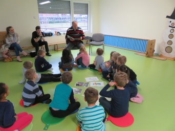 Mann liest einer Kindergruppe vor.