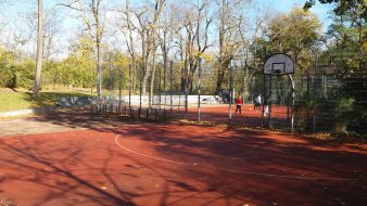 eingezäunter Bolzplatz und Basketballfläche mit Ständer und Korb
