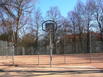 eingezäunter Bolzplatz mit Fußballtor und Basketballfeld mit Ständer und Korb