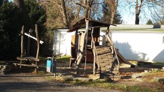 große Sandfläche mit Kletterturm aus Holz und Rutsche