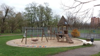 große Sandfläche mit Kletterturm aus Holz und Vogelnestschaukel