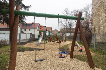 ein Spielplatz mit einer Doppelschaukel im Vordergrund