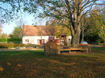 Spielwand mit Sitzmöglichkeiten um einen Baum