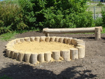 runder Sandkasten und zwei Balancierbalken aus Holz